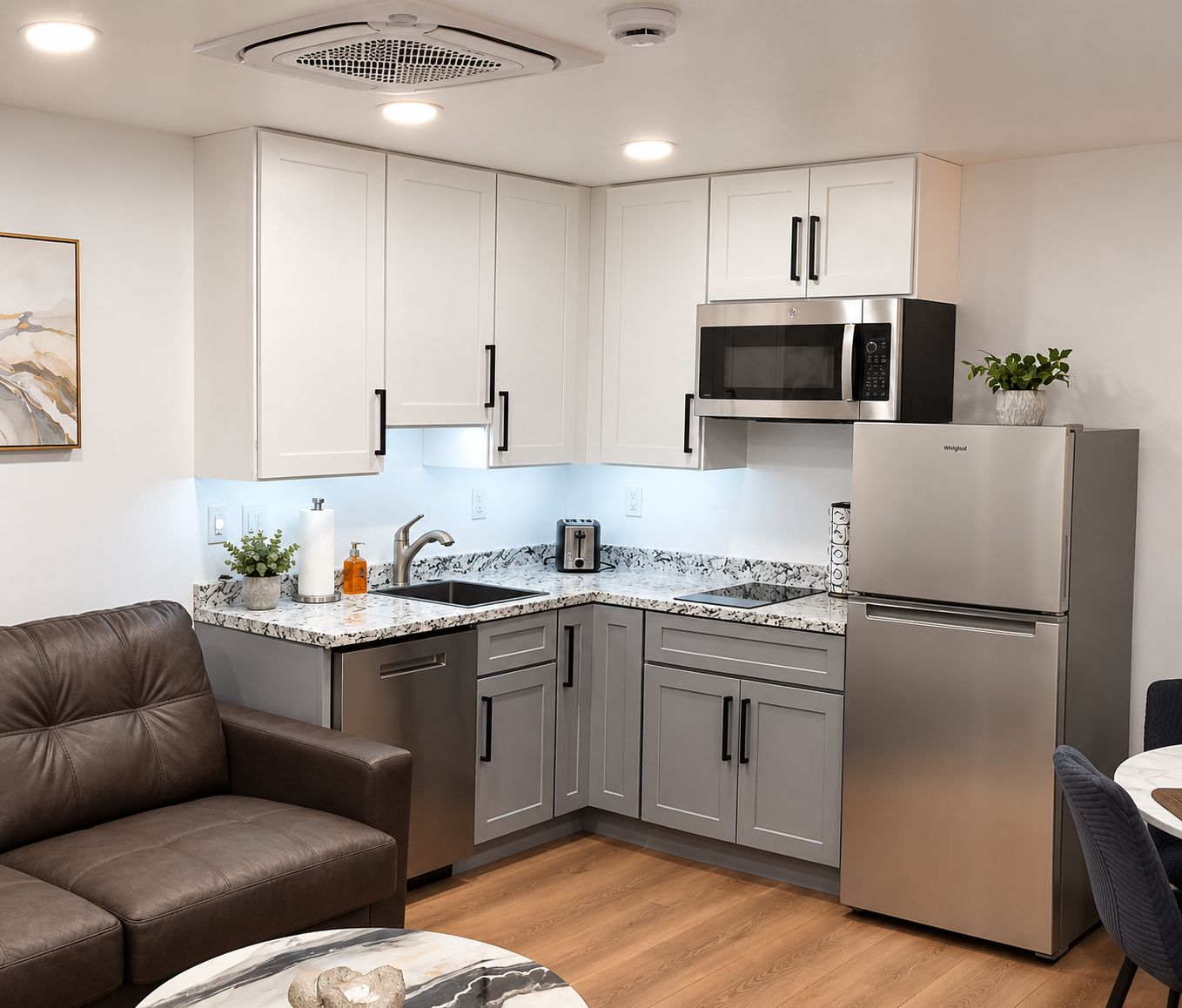 Cozinha moderna com eletrodomésticos de aço inoxidável, bancada de mármore e armários cinzentos.