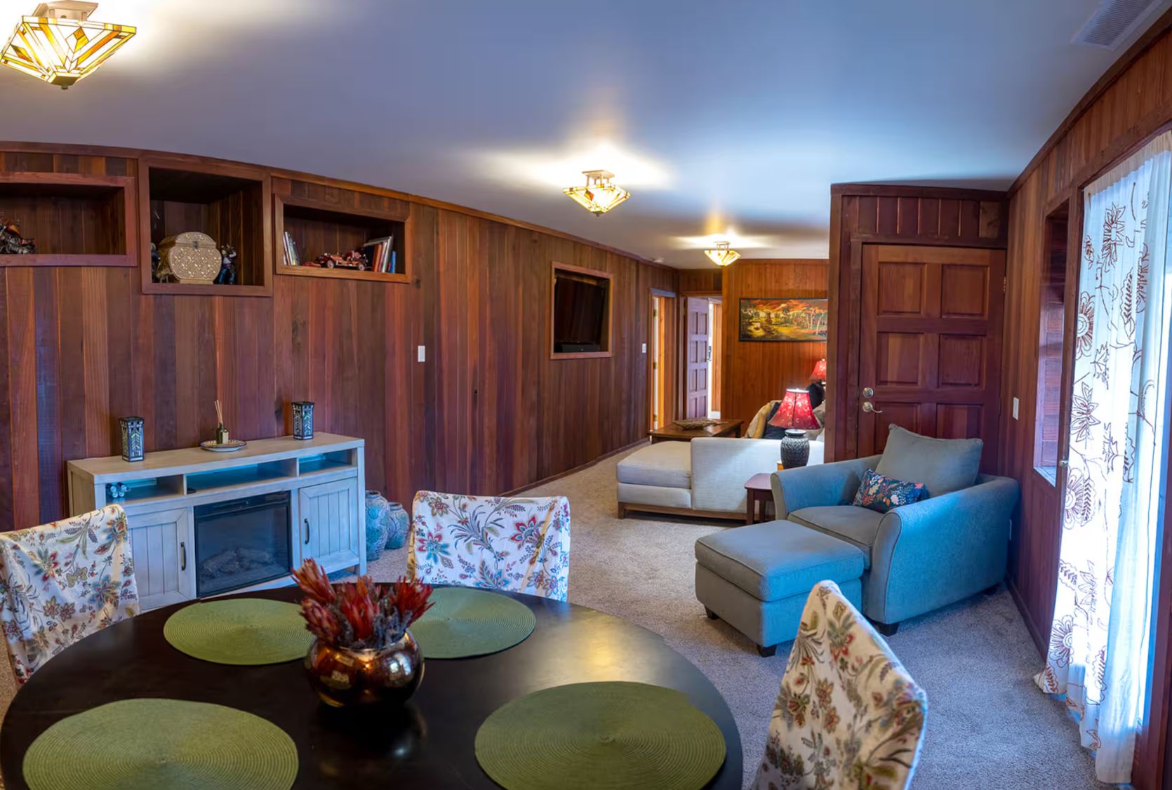 A cozy living room with a fireplace, a dining table with placemats, and a sofa.