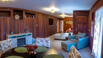 A cozy living room with a fireplace, a dining table with placemats, and a sofa.