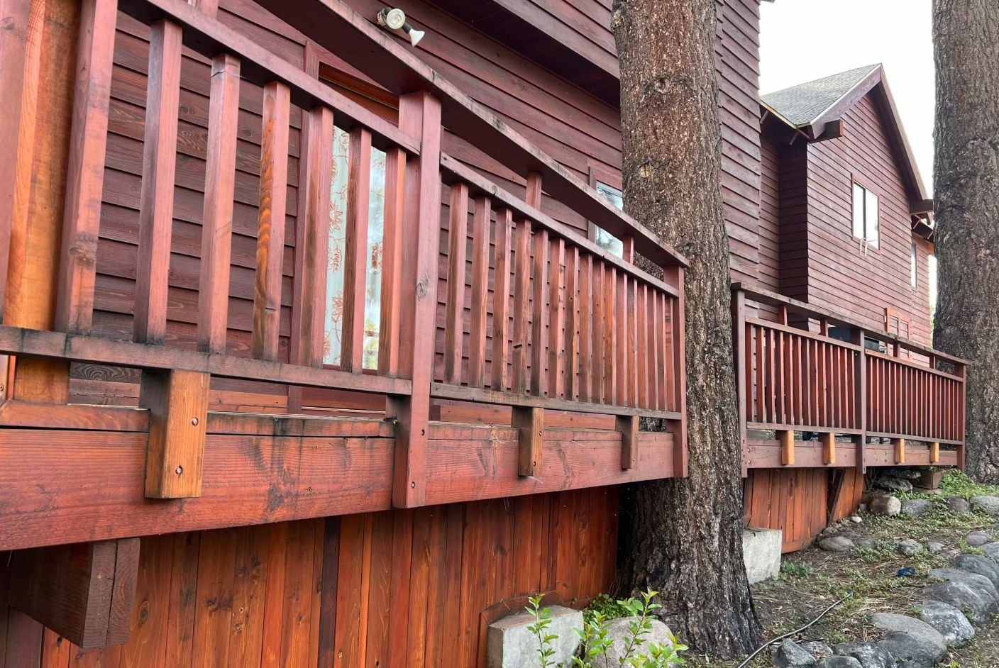A wooden building with a balcony and a tree trunk.