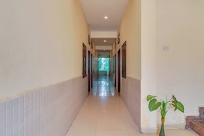 A corridor with doors on both sides, leading to a bright room with a window. - Hotel O by OYO Second Home Residency (Dehradun)