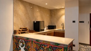 A modern kitchen with a marble backsplash, a microwave, and a coffee maker on the counter. - Golden Knot Luxury Hotel (Thimphu)