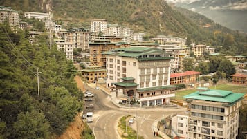 A mountainous town with multi-story buildings, a winding road, and lush greenery.
