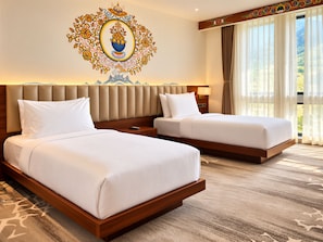 A hotel room with two beds, a decorative wall mural, and a large window with curtains. - Golden Knot Luxury Hotel (Thimphu)