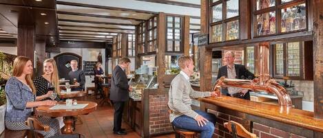 Eine Bar mit Hockern, einem Barkeeper und einer Theke mit Kupferrohren.