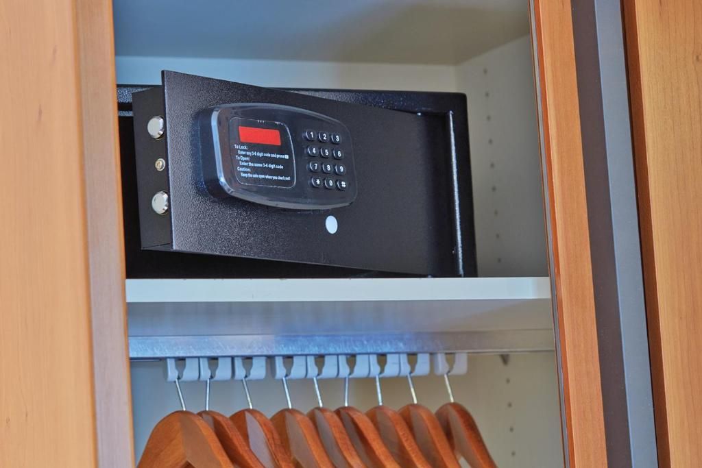 Un dispositivo electrónico negro con teclado y un botón rojo sobre una estantería.
