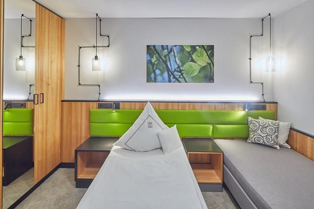 Una habitación moderna con cama, asientos verdes e iluminación en la pared.
