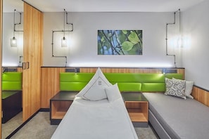 A modern room with a bed, green seating, and wall-mounted lights. - Landhotel Naafs-Häuschen (Lohmar)