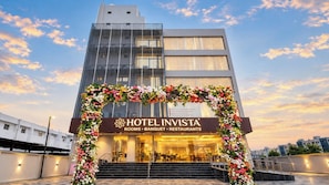 Entrada de un hotel con un arco floral, un cartel que dice Hotel Invista y vistas de los edificios circundantes.