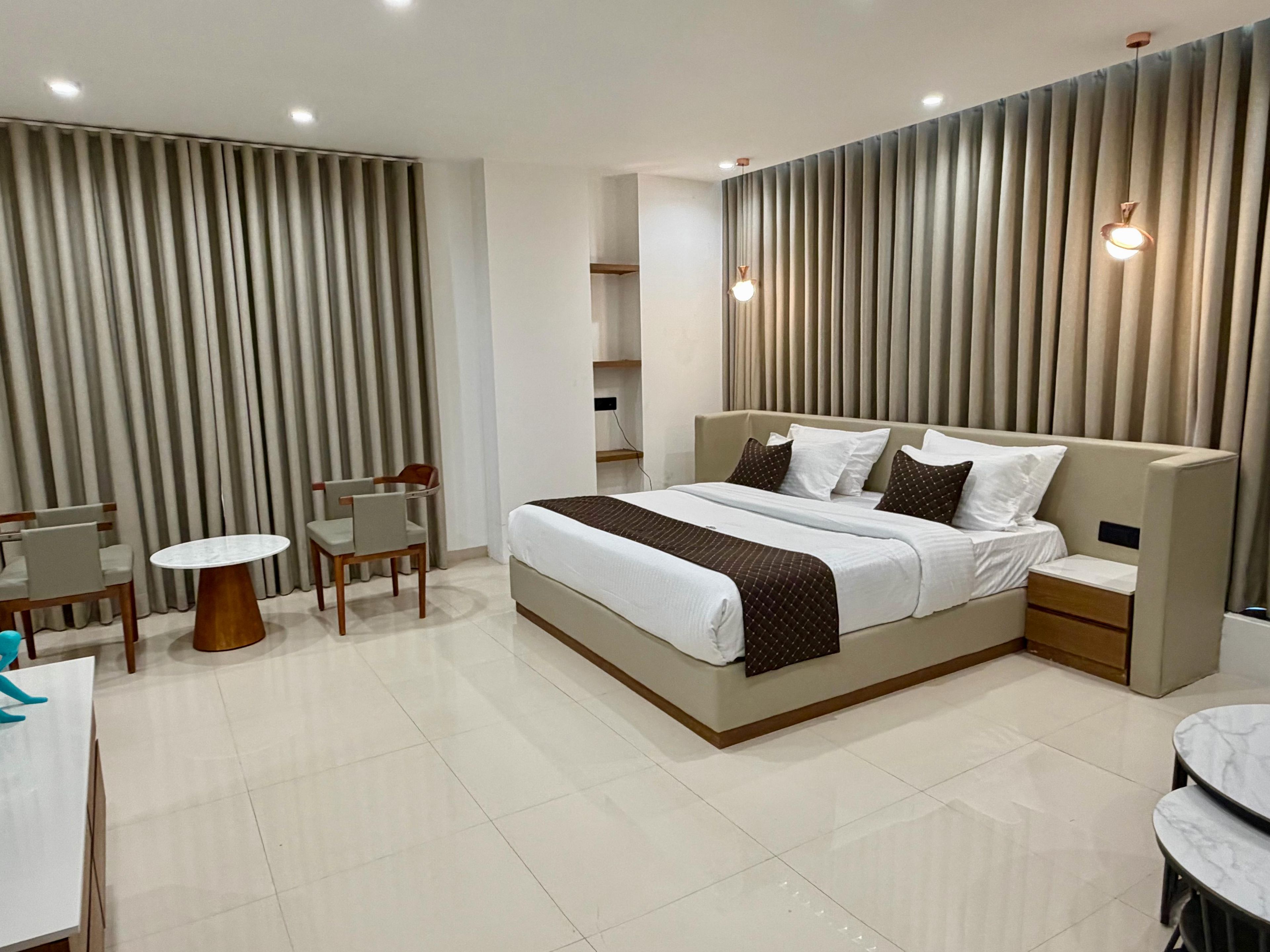 Una habitación de hotel moderna con una cama grande, mesitas de noche, un escritorio y sillas.