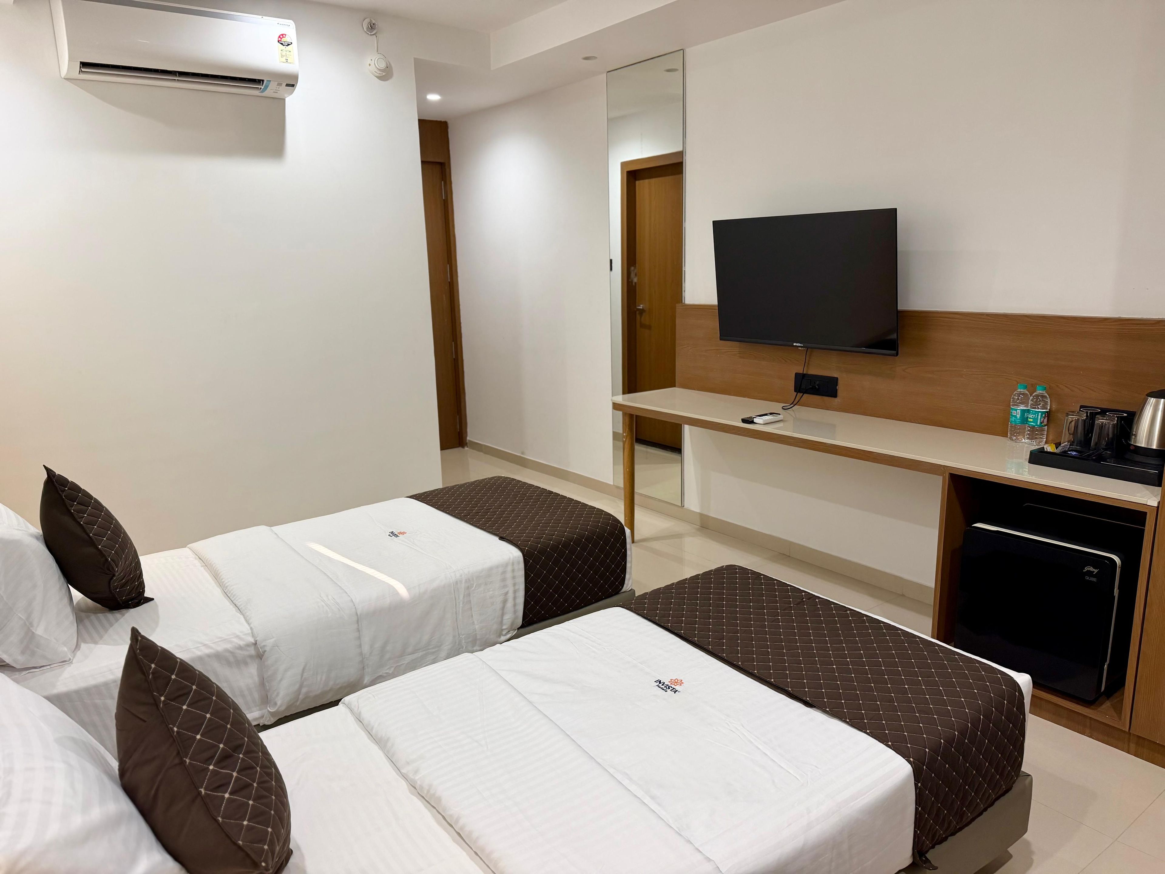Habitación de hotel con dos camas, un escritorio, un televisor y un minibar.