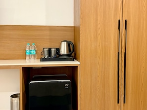 Una kitchenette con cafetera, dos botellas de agua y un refrigerador pequeño.