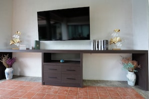 A flat-screen TV mounted on a wall above a dark wooden cabinet with drawers. - Quiet 3BR Pool Villa in Soi Naya near Nai Harn Beach (Tambon Rawai)