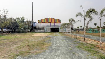 An open area with a building in the background, a dirt path leading to it, and sparse vegetation.