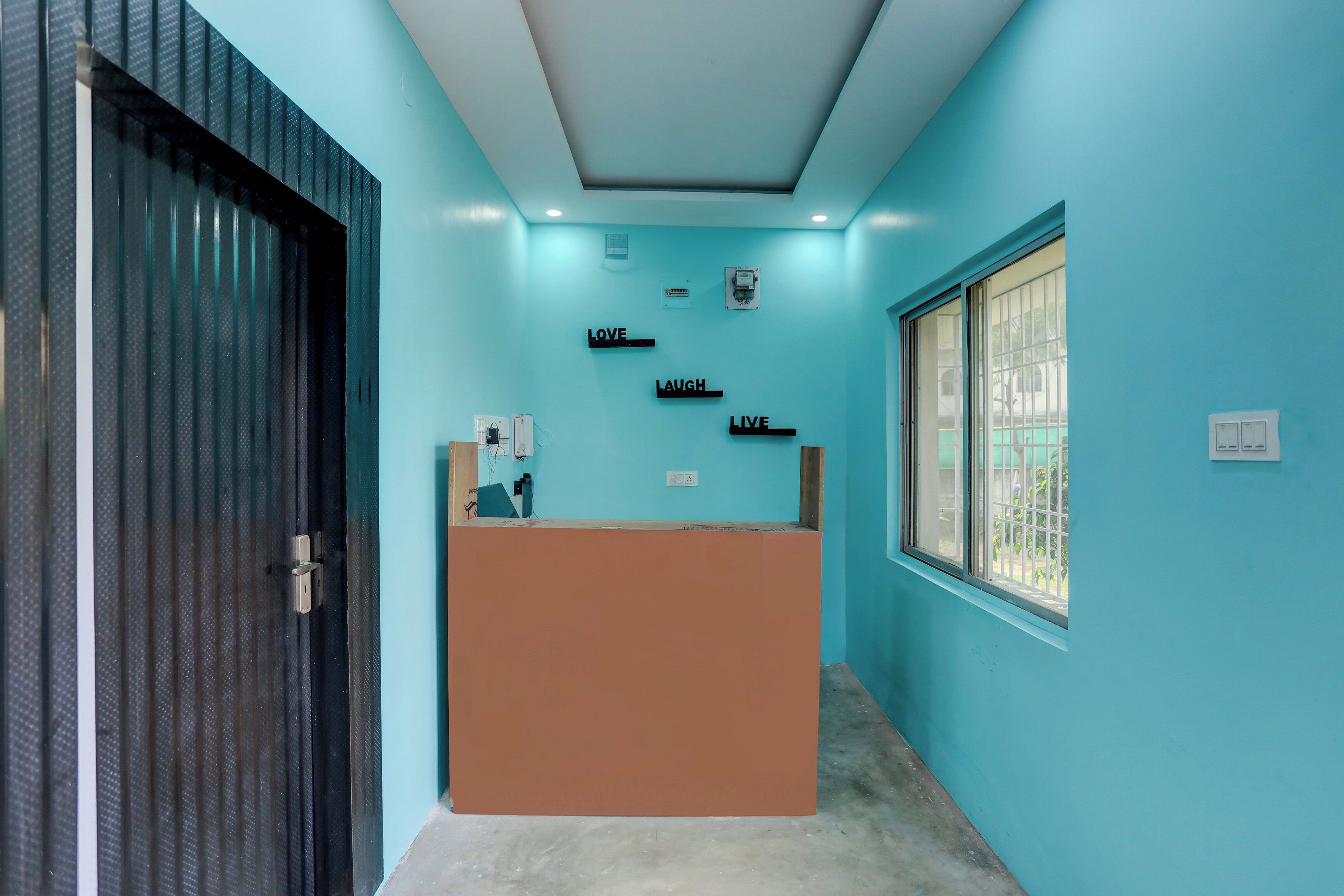 Een receptiebalie met een blauwe wand en een raam met metalen tralies.