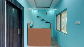 Een receptiebalie met een blauwe wand en een raam met metalen tralies.