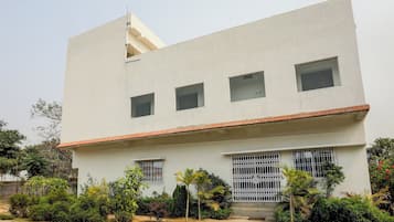 A modern building with a flat roof, multiple windows, and a gated entrance.