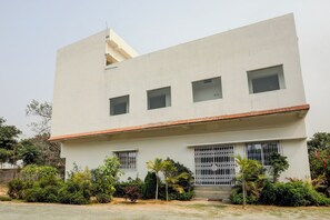 Un edificio moderno con tejado plano, varias ventanas y entrada protegida por una reja.