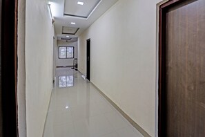 A corridor with a tiled floor, a door at the end, and a window with bars.