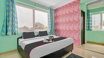 A hotel room with a bed, a window, a door, and a wall with a floral pattern.