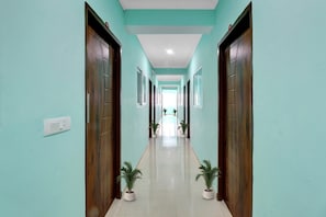 A hallway with teal walls, wooden doors, and potted plants. - Super Collection O The Kailash Hotel (Dehradun)
