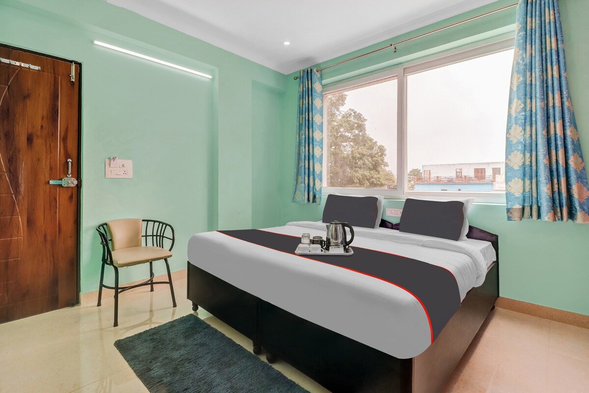 A hotel room with a bed, a chair, a window with curtains, and a view of the outside.