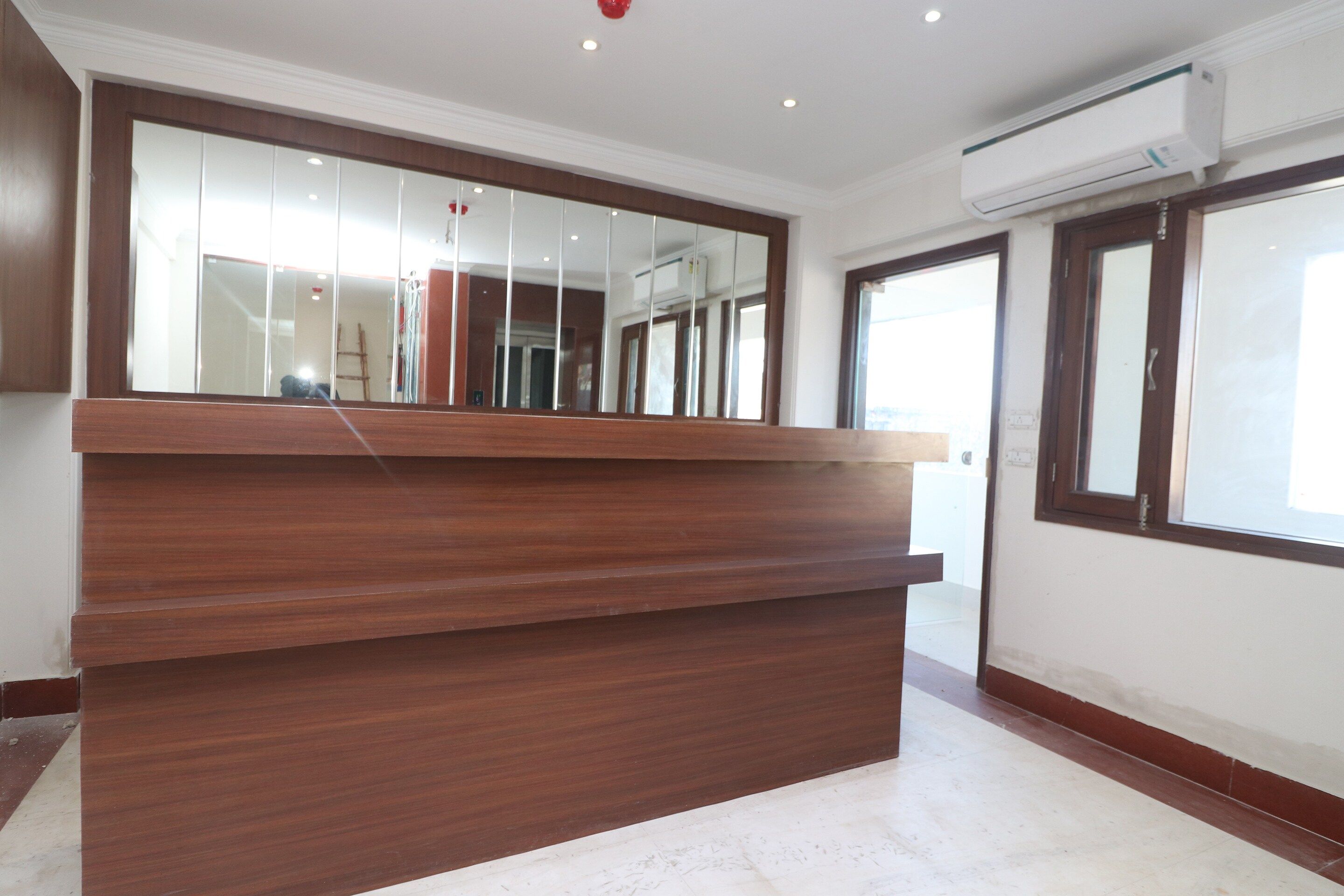 A reception desk with a mirror, a ceiling light, and an air conditioning unit.
