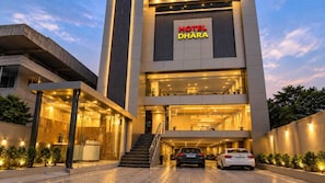 A hotel with a modern facade, a visible entrance, and a car parked in front. - Hotel O Dhara (Dehradun)