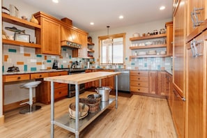 A modern kitchen with wooden cabinets, a stainless steel sink, and a central island with stools.