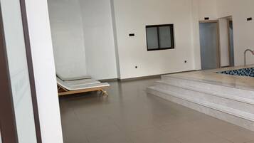 Une pièce spacieuse avec un sol carrelé, une petite fenêtre et un escalier menant à un balcon.