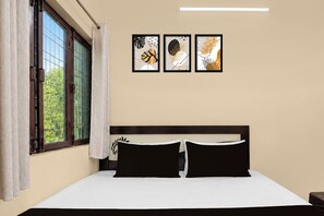 Un dormitorio con una cama, una ventana con cortinas y tres cuadros en la pared.