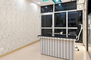 A modern office space with a glass partition, a black desk, and a chair. - Hotel O Uttarakhand B/b (Dehradun)