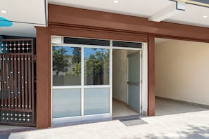 A modern building entrance with a glass door and a metal gate. - Hotel O Uttarakhand B/b (Dehradun)