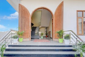 A building entrance with a staircase leading to an upper level, flanked by two large wooden doors and a central archway. - Hotel O PCR Continental (Dehradun)