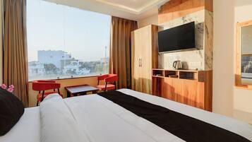 A hotel room with a bed, a TV mounted on the wall, a small table, and a chair.