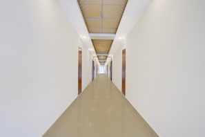 A long, straight hallway with a polished floor and a patterned ceiling. - Hotel O PCR Continental (Dehradun)