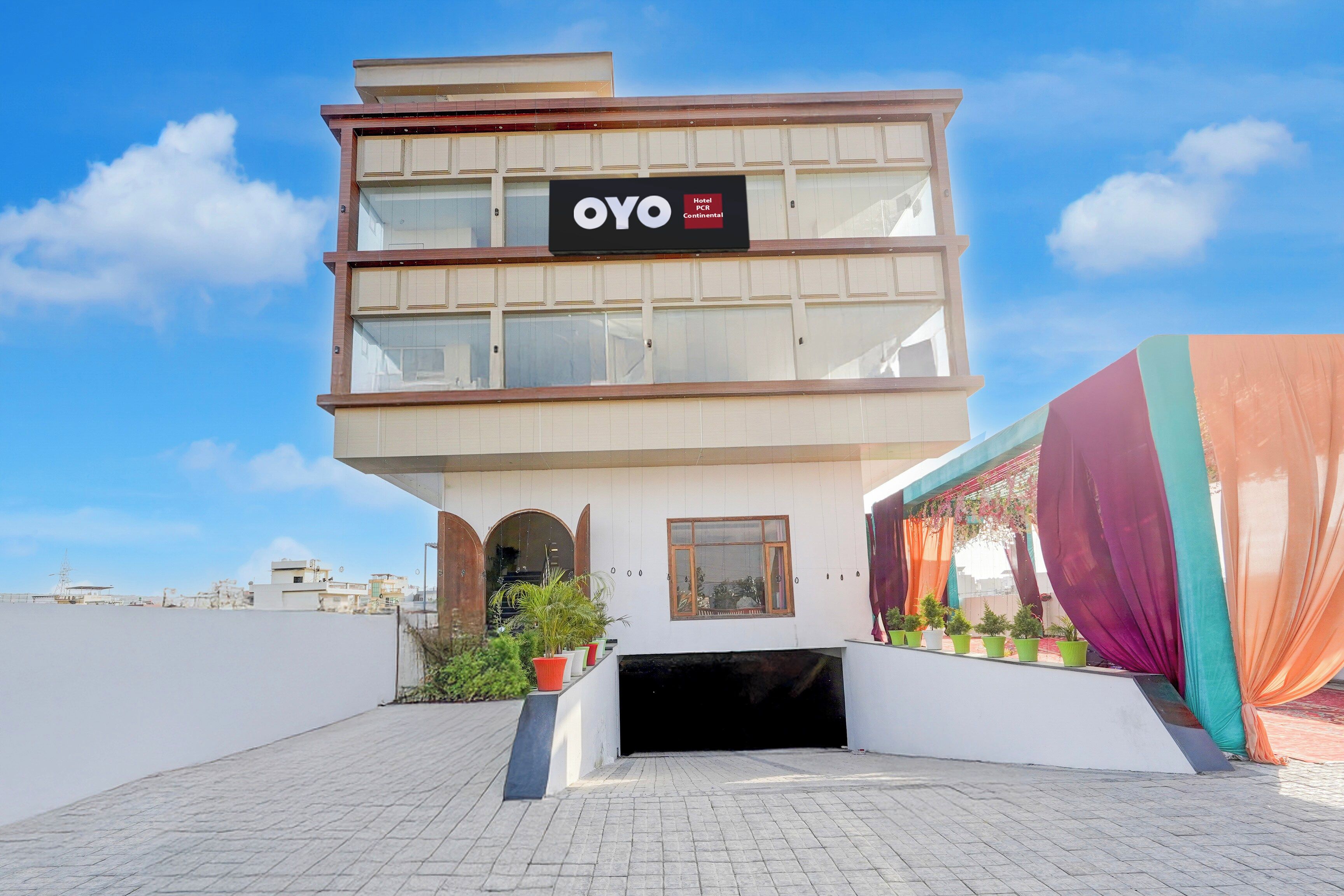 A hotel named OYO Continental with a modern design, featuring a flat roof, large windows, and a signboard.