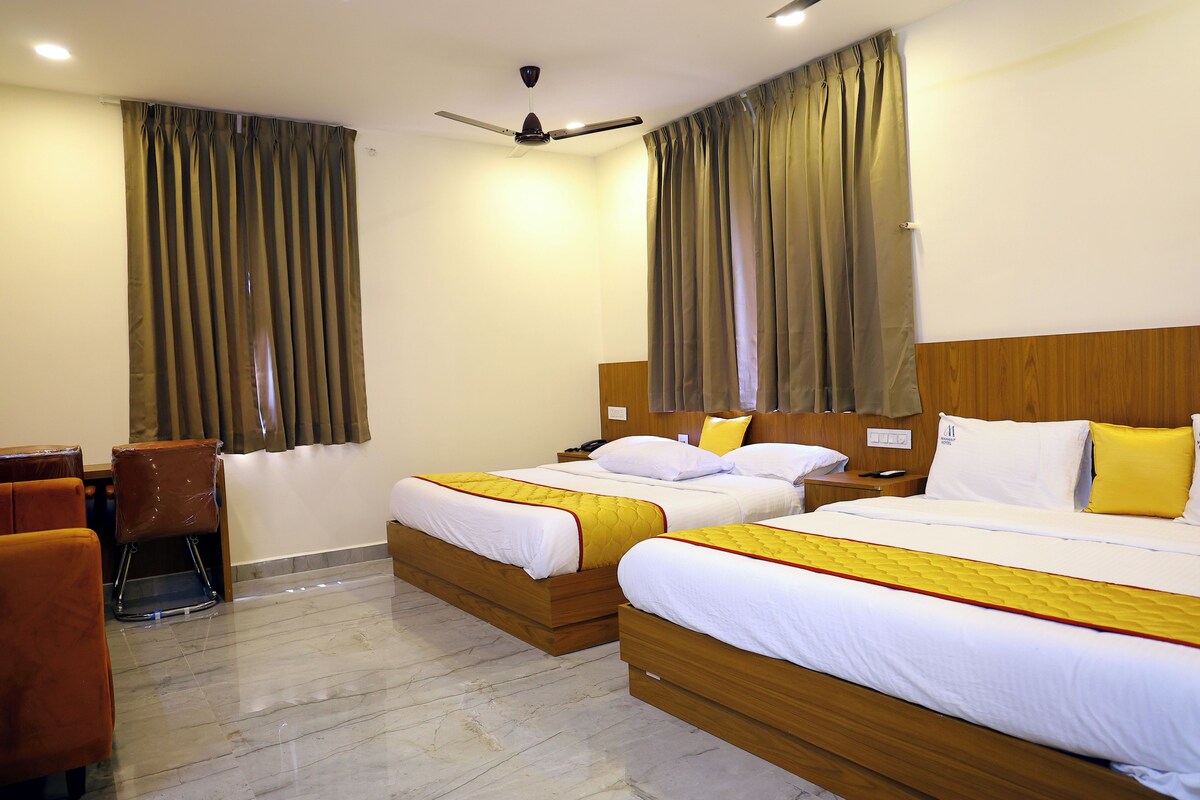 A hotel room with two beds, a desk, and a chair.