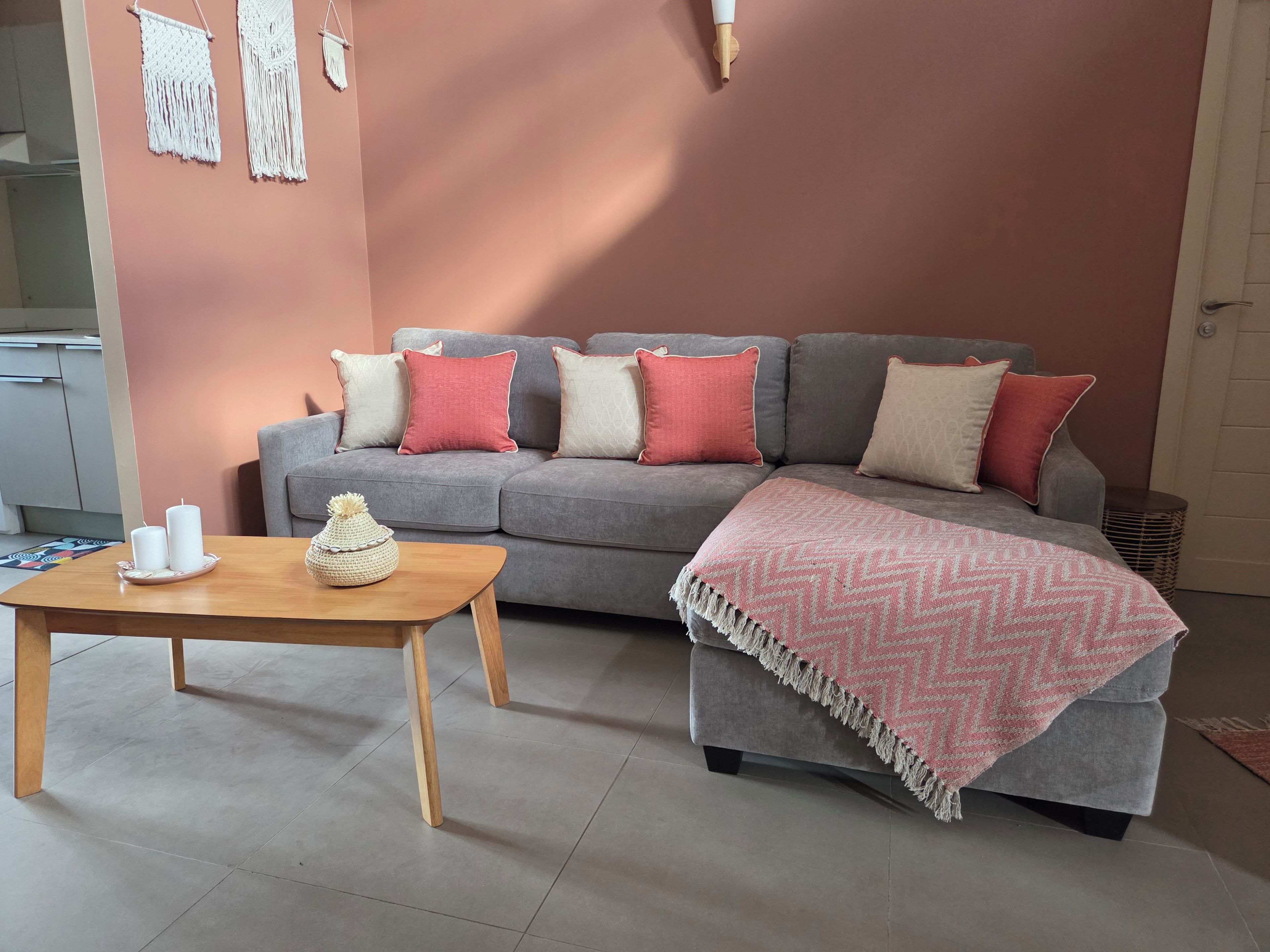 A living room with a grey sofa, a wooden coffee table, and a pink patterned throw blanket.