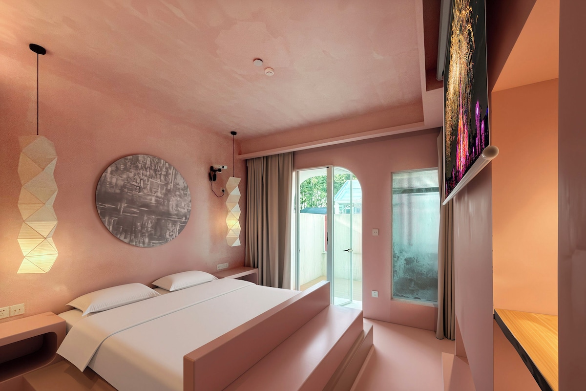 Un dormitorio moderno con una cama grande, una obra de arte circular en la pared y vistas a través de una puerta de cristal.