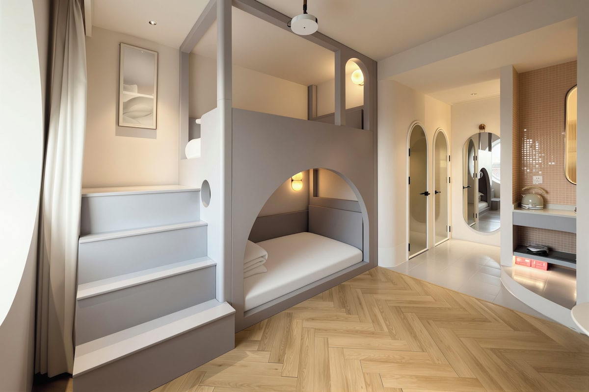 Un dormitorio moderno con una litera, un espejo y un piso de madera con patrón de espiga.