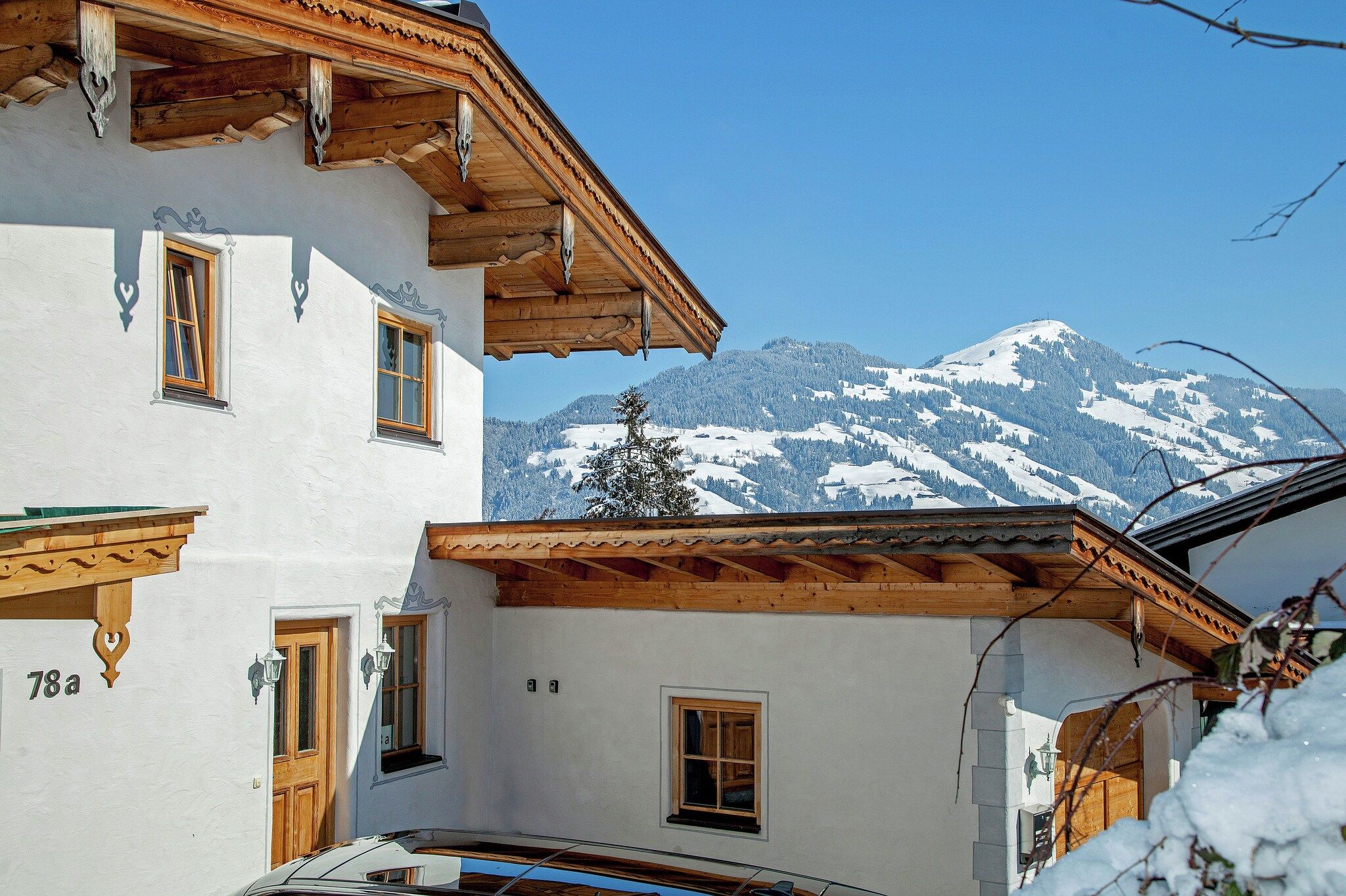 Een klassiek chalet met een houten gevel, meerdere ramen en uitzicht op besneeuwde bergen.