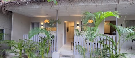 A building with a thatched roof, white railings, and a staircase leading to a door.