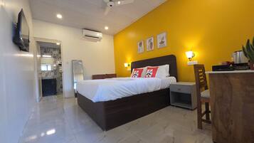 A hotel room with a bed, bedside table, and a desk with a chair.