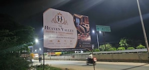 Un gran cartell publicitari de l'Hotel i Restaurant Heaven Valley amb serveis com habitacions de luxe, un restaurant, Wi-Fi gratuït i aparcament.