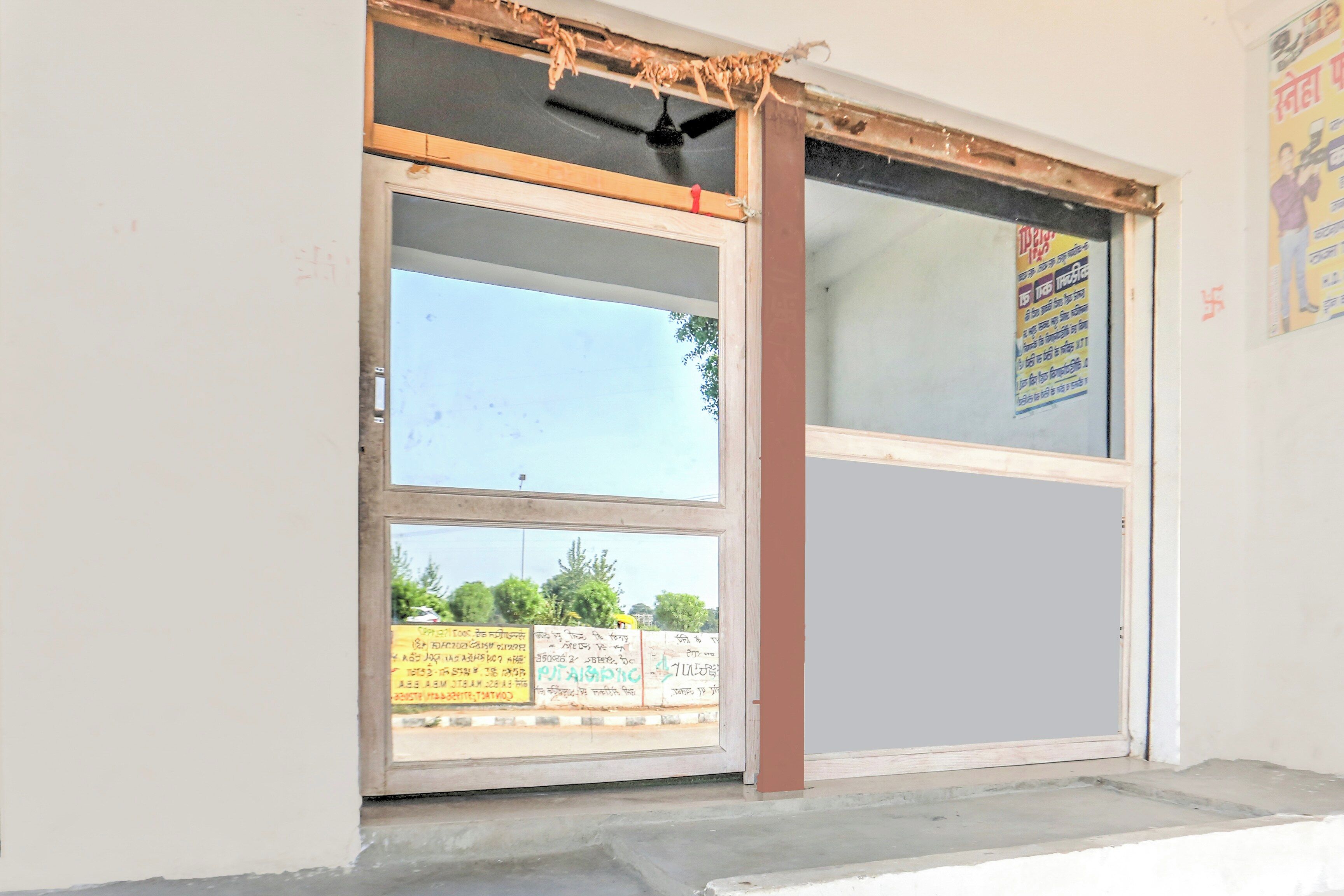 A building entrance with a glass door and a poster on the wall.