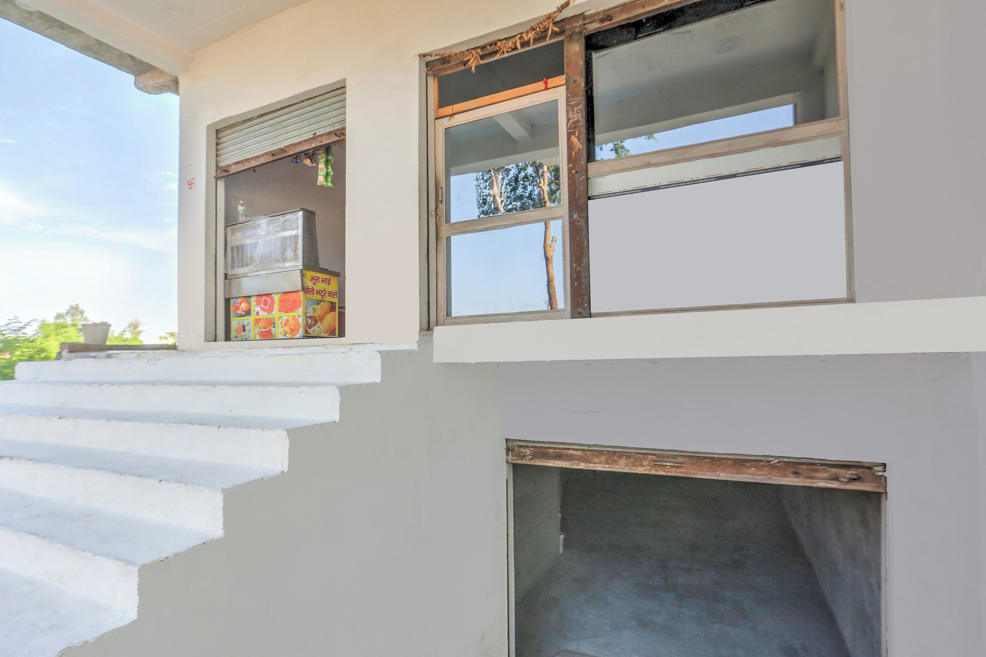 A staircase leading to a building entrance with a window and a small shop on the ground floor.