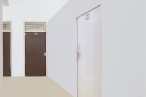 A hallway with two doors, one marked with the number 102, and a white door with a lock. - Hotel O VS Palace (Etawah)
