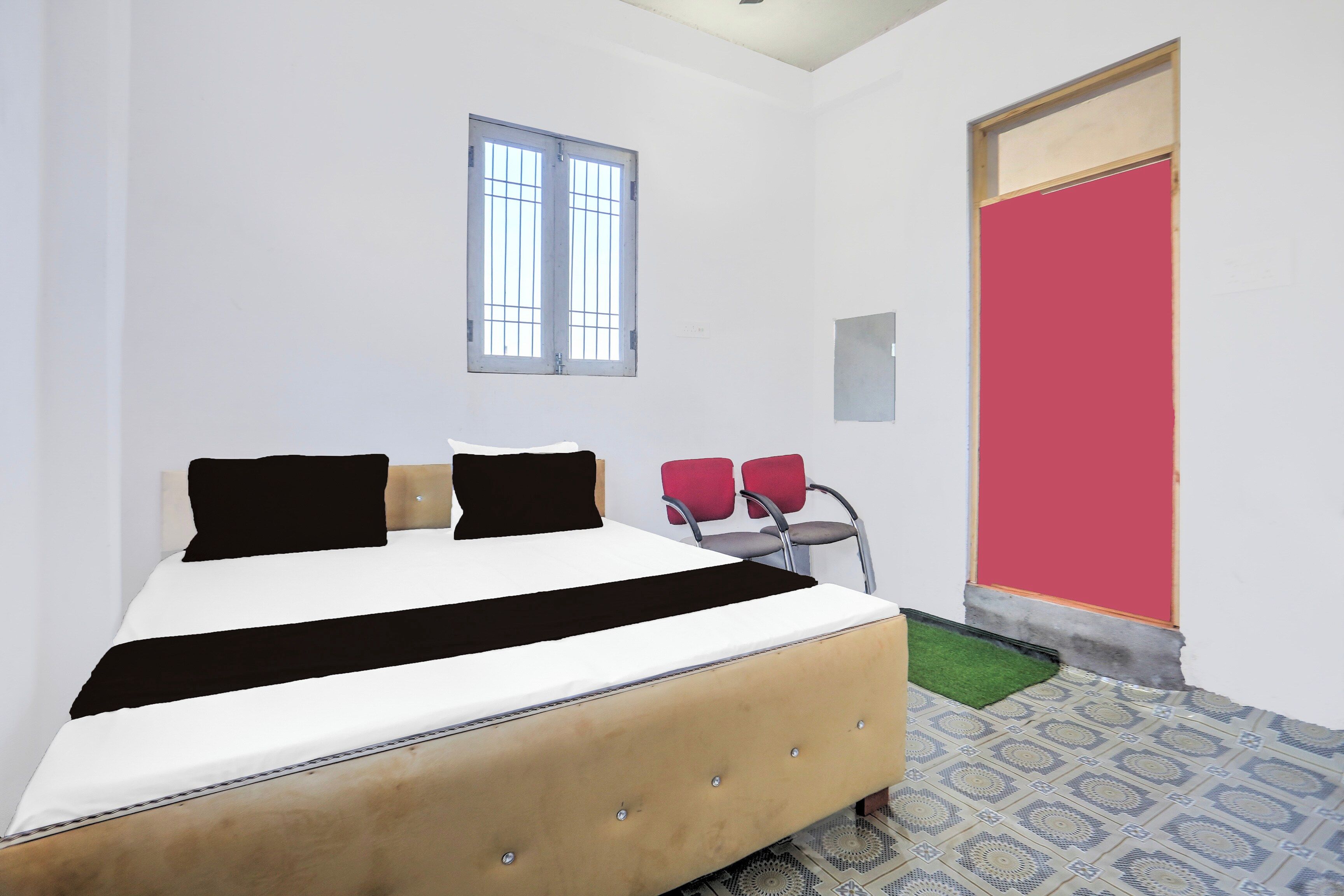 A room with a bed, a window, a door, and a small seating area.
