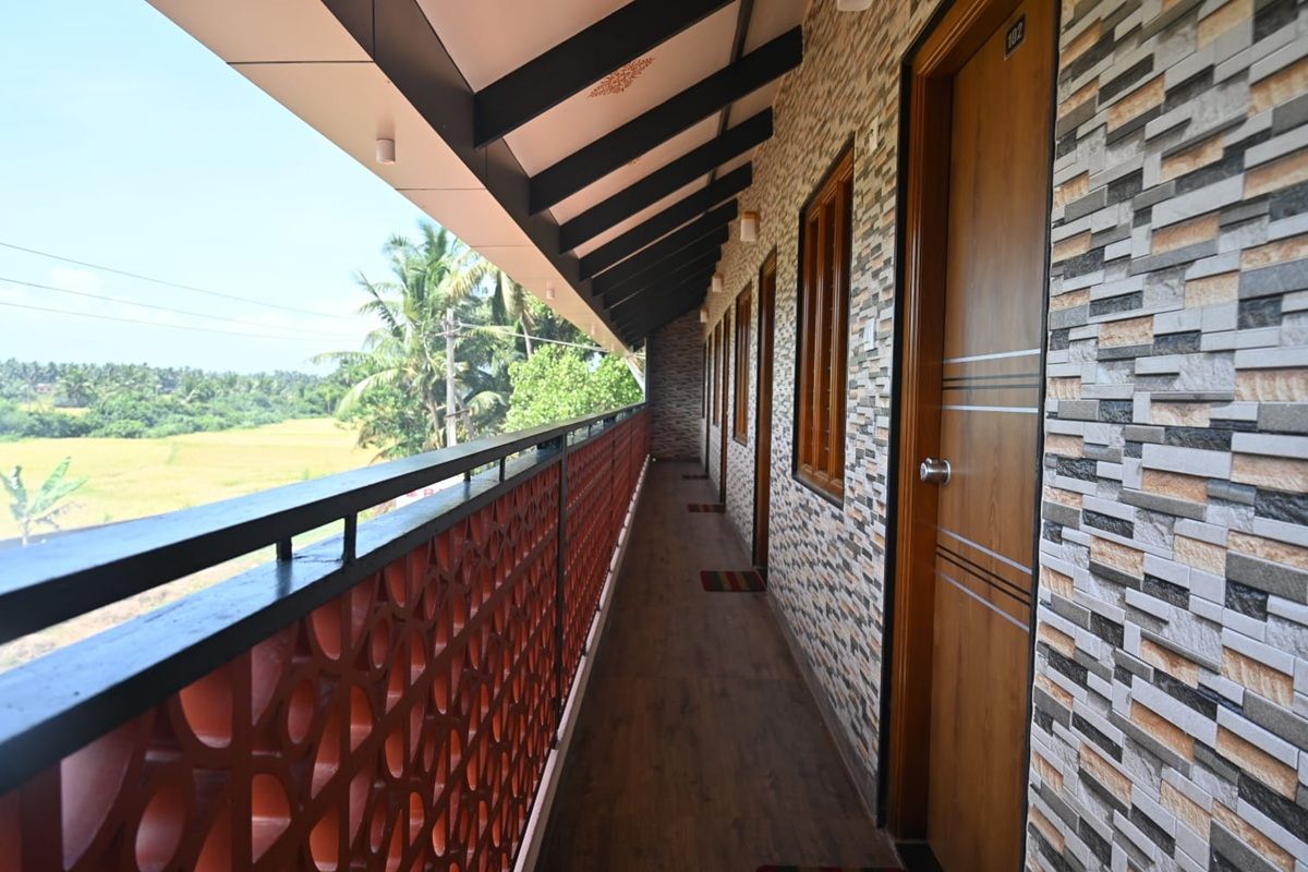 A corridor with a patterned wall, a wooden door, and a balcony with a red railing.